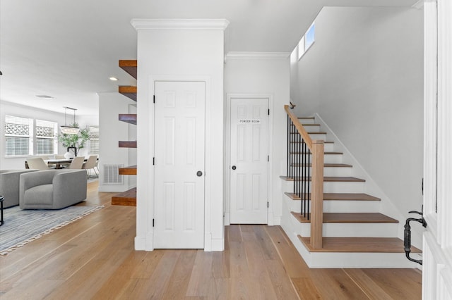 stairway with ornamental molding, wood finished floors, visible vents, and recessed lighting