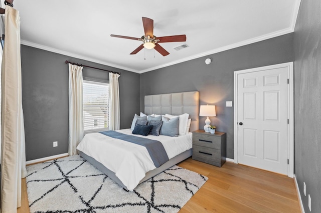 bedroom with ornamental molding, wood finished floors, visible vents, and baseboards