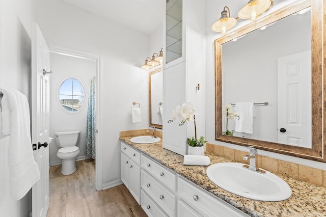 full bath featuring double vanity, wood finished floors, a sink, and toilet