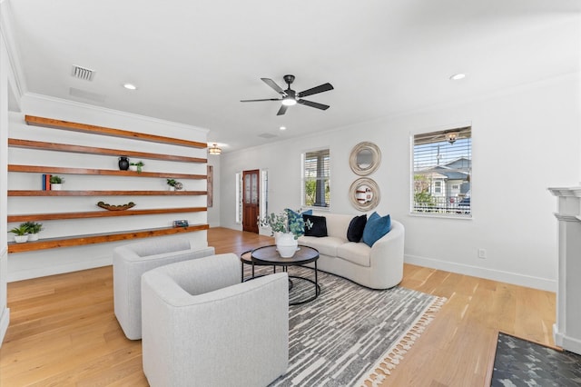 living area featuring light wood-style floors, visible vents, ornamental molding, and baseboards