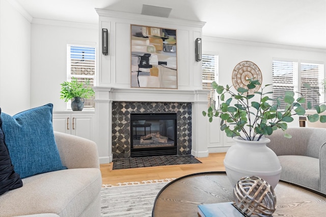 living room featuring light wood finished floors, a fireplace, and crown molding