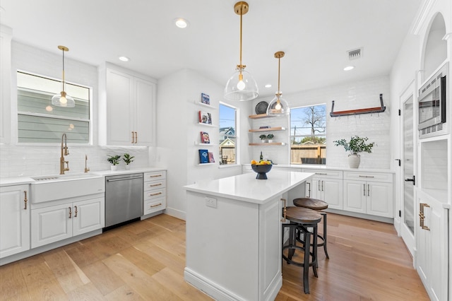 kitchen with a sink, visible vents, appliances with stainless steel finishes, light wood-type flooring, and open shelves