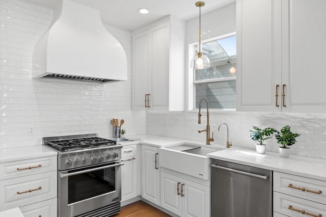 kitchen featuring appliances with stainless steel finishes, premium range hood, a sink, and tasteful backsplash