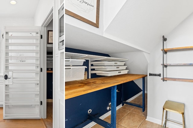 bedroom with tile patterned flooring, vaulted ceiling, and baseboards