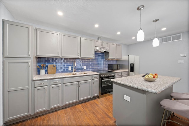 kitchen featuring stainless steel appliances, gray cabinets, visible vents, hanging light fixtures, and a sink