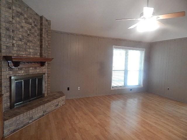 unfurnished living room with lofted ceiling, light wood-style floors, ceiling fan, and a fireplace