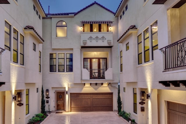 mediterranean / spanish-style home with driveway, a tile roof, an attached garage, and stucco siding