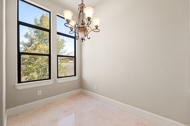 empty room featuring baseboards and a notable chandelier