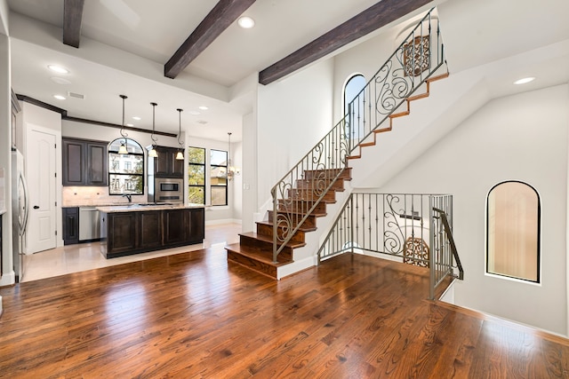 kitchen featuring baseboards, beamed ceiling, wood finished floors, and a center island