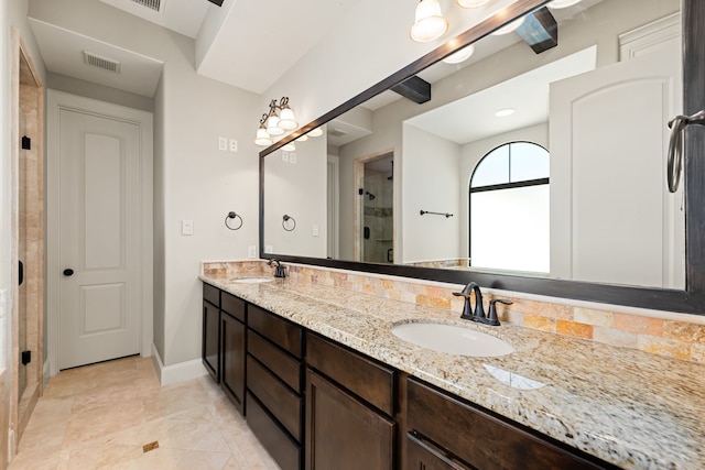 bathroom with double vanity, visible vents, a stall shower, a sink, and baseboards