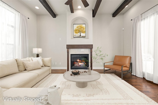 living room with a wealth of natural light, dark wood-style flooring, a glass covered fireplace, and baseboards