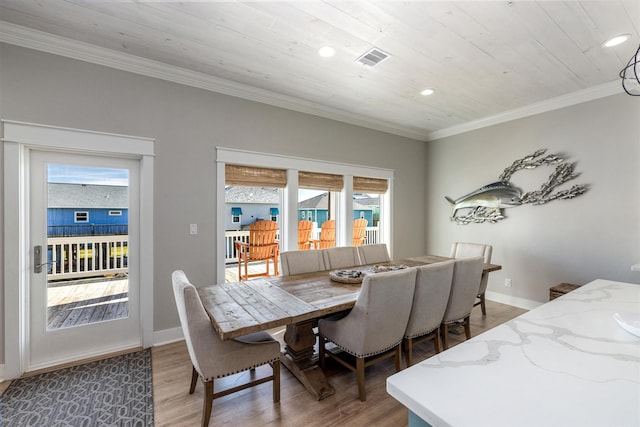 dining area with light wood-style flooring, baseboards, visible vents, and ornamental molding