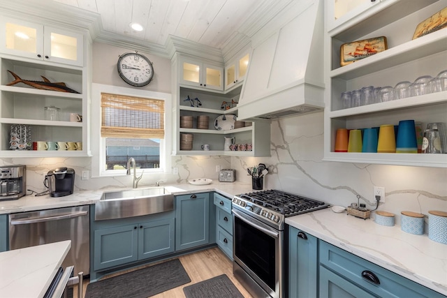 kitchen featuring open shelves, custom exhaust hood, a sink, stainless steel appliances, and blue cabinets