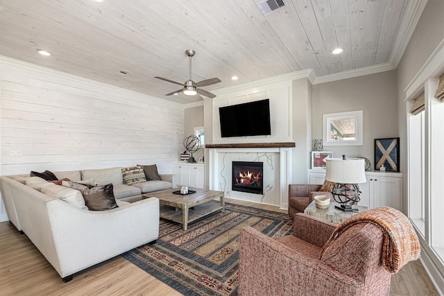 living room featuring a high end fireplace, visible vents, light wood-type flooring, ornamental molding, and wooden ceiling