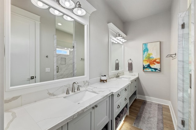 bathroom with a stall shower, wood finished floors, baseboards, and a sink