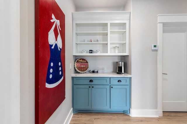 bar with baseboards, light wood-style flooring, and a dry bar