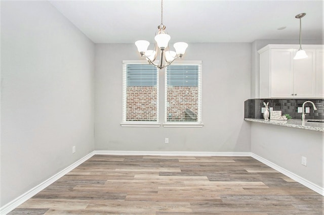 unfurnished dining area with light wood-type flooring, baseboards, and a sink