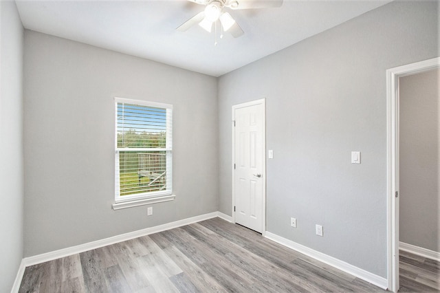 spare room featuring a ceiling fan, baseboards, and wood finished floors