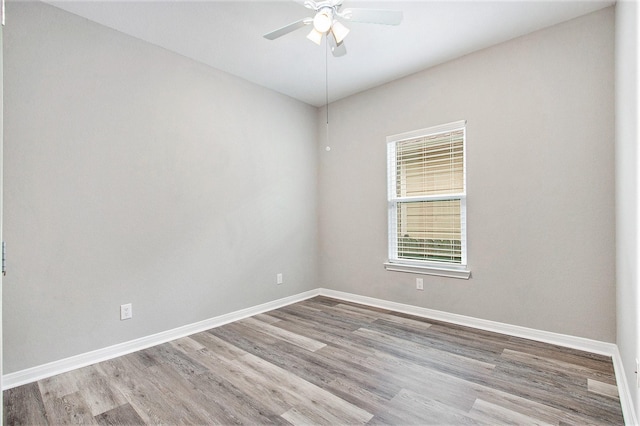 empty room featuring ceiling fan, baseboards, and wood finished floors