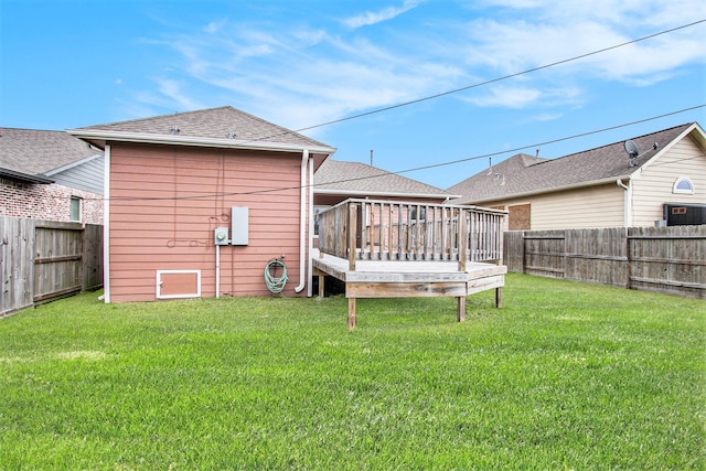 rear view of house featuring a deck, a shingled roof, a lawn, and a fenced backyard