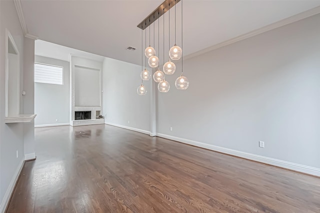 unfurnished living room featuring dark wood-type flooring, visible vents, baseboards, a brick fireplace, and crown molding