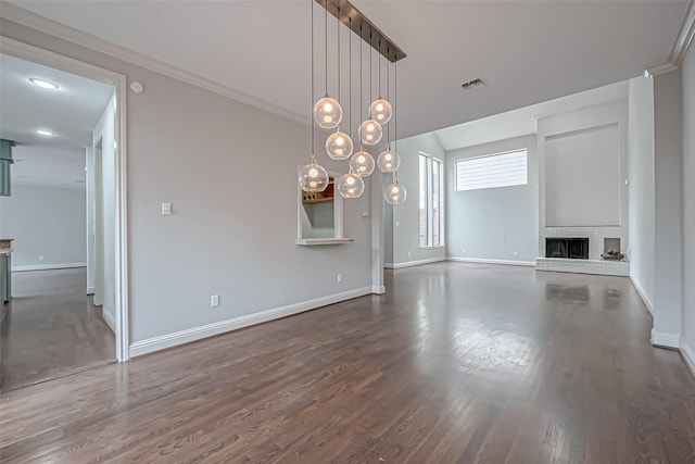 unfurnished living room with visible vents, baseboards, dark wood-style floors, crown molding, and a brick fireplace