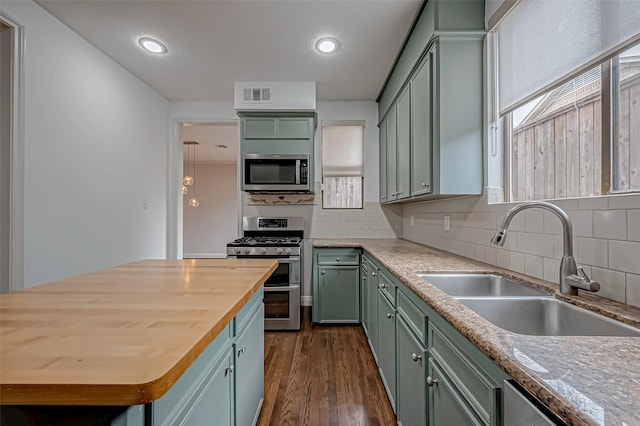 kitchen with stainless steel appliances, visible vents, a sink, and green cabinets