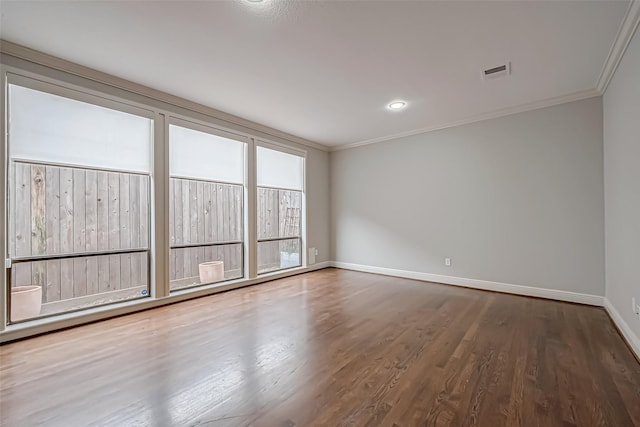 spare room featuring baseboards, visible vents, crown molding, and wood finished floors