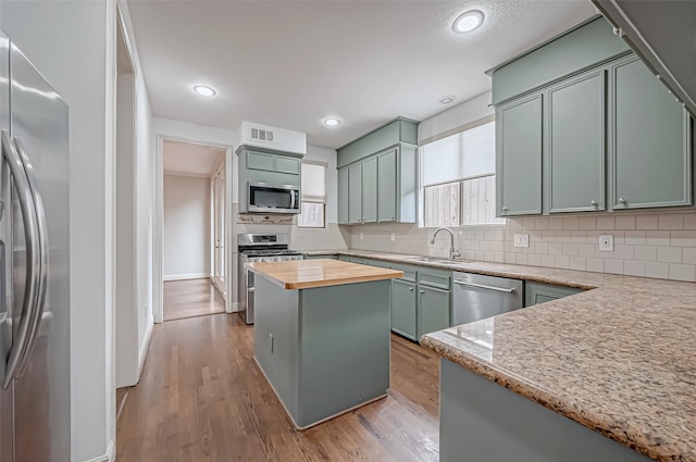 kitchen featuring appliances with stainless steel finishes, wooden counters, decorative backsplash, and light wood finished floors