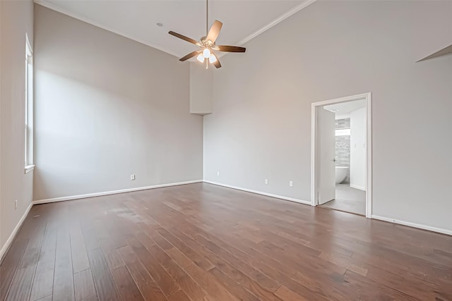 unfurnished room with dark wood-style floors, ceiling fan, a high ceiling, and baseboards