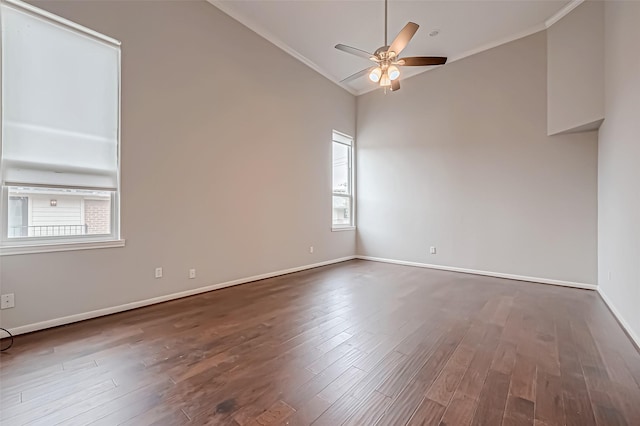 empty room featuring vaulted ceiling, dark wood-style flooring, plenty of natural light, and ceiling fan