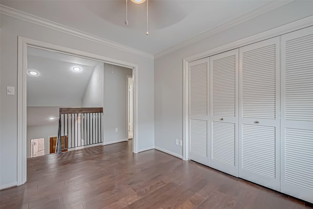 interior space with wood finished floors, baseboards, a closet, attic access, and crown molding