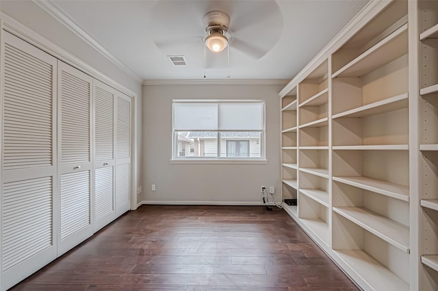 interior space featuring baseboards, visible vents, dark wood-style floors, crown molding, and a closet