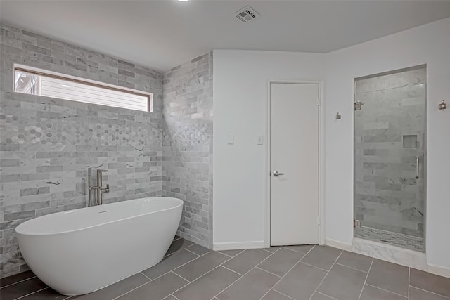 bathroom with visible vents, tile patterned floors, a freestanding bath, a shower stall, and tile walls