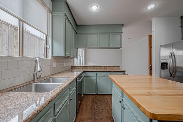 kitchen with a sink, appliances with stainless steel finishes, light stone countertops, dark wood-style floors, and tasteful backsplash