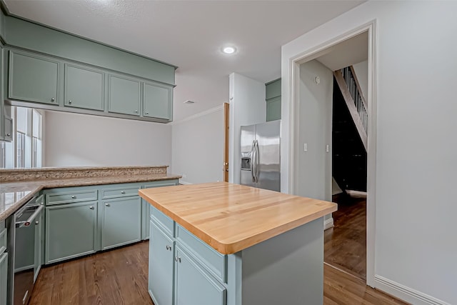 kitchen with butcher block counters, a kitchen island, ornamental molding, dark wood-style flooring, and stainless steel appliances