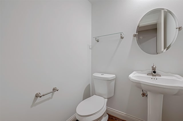 half bath featuring toilet and baseboards