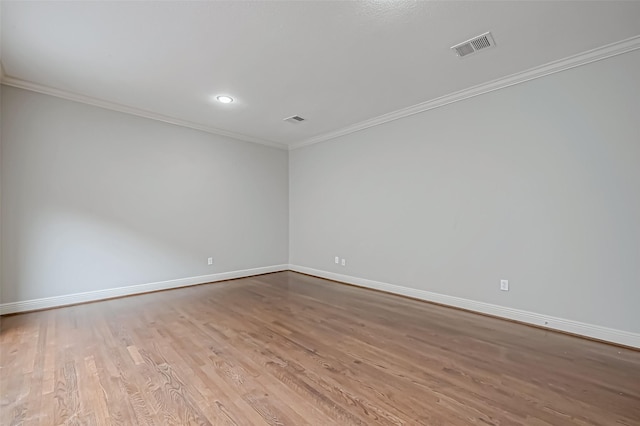 empty room with ornamental molding, visible vents, light wood-style floors, and baseboards