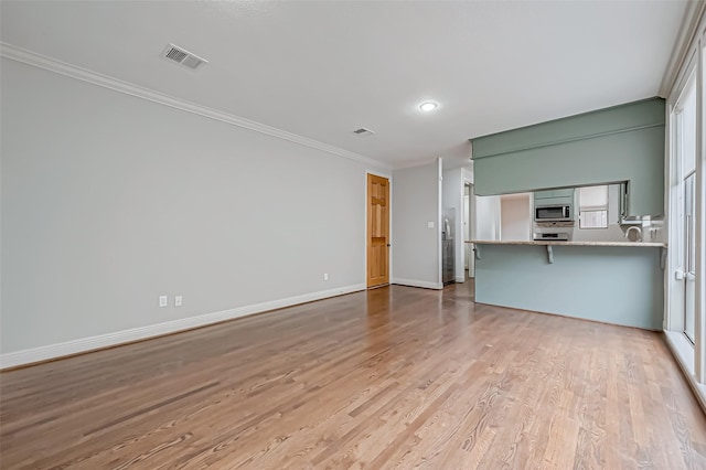 unfurnished living room with baseboards, light wood finished floors, visible vents, and crown molding