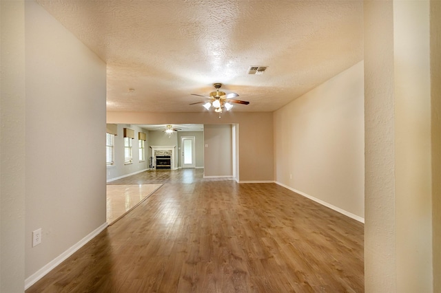 unfurnished living room with baseboards, a fireplace, visible vents, and wood finished floors