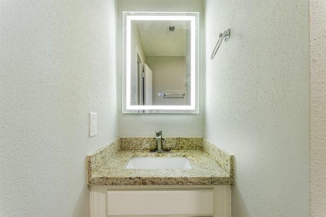 bathroom featuring a textured wall and vanity