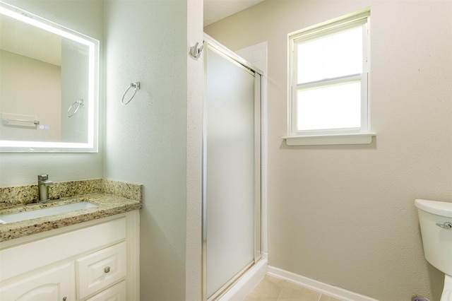 full bathroom with vanity, a shower stall, toilet, and baseboards