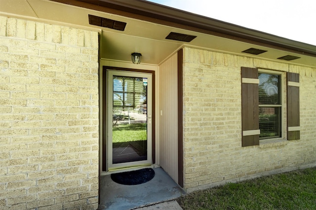 entrance to property with visible vents and brick siding