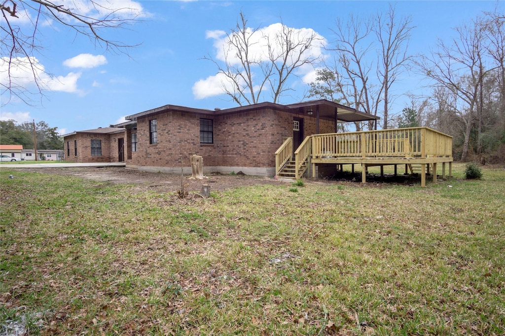 view of property exterior featuring a deck, a lawn, and brick siding
