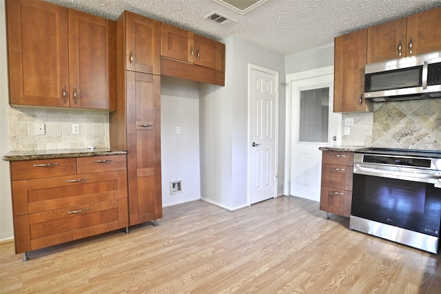 kitchen with stove, wall oven, light wood-style flooring, and stainless steel microwave