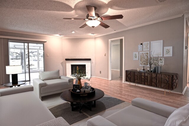 living area with wood finished floors, a ceiling fan, a textured ceiling, and crown molding