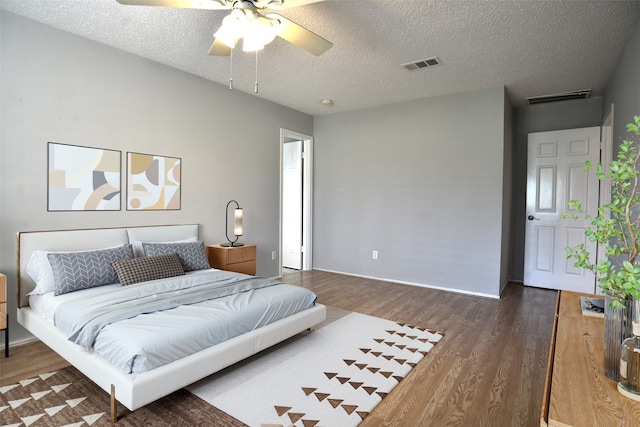 bedroom featuring a textured ceiling, visible vents, wood finished floors, and baseboards