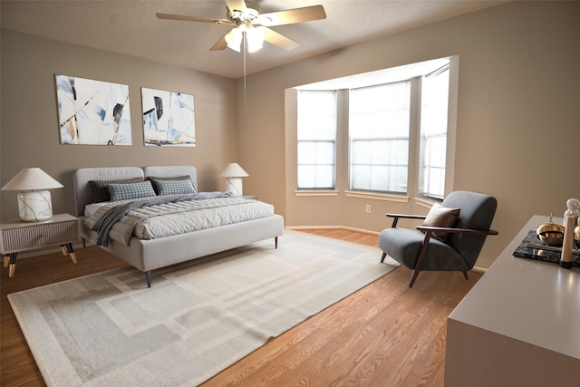 bedroom with ceiling fan, a textured ceiling, and light wood-style flooring