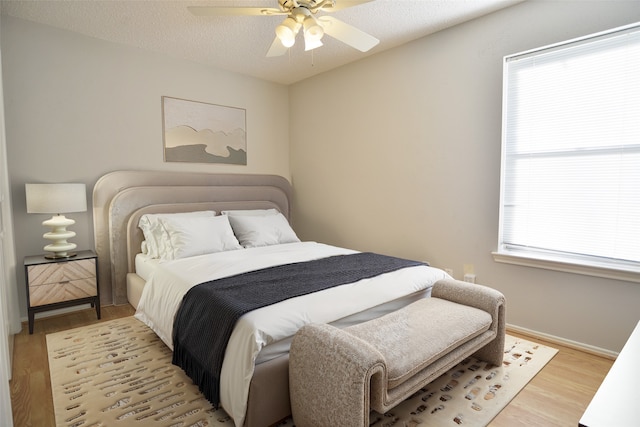 bedroom with light wood finished floors, ceiling fan, and baseboards