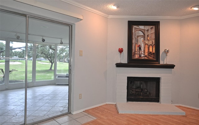 unfurnished living room with a textured ceiling, wood finished floors, crown molding, and a brick fireplace